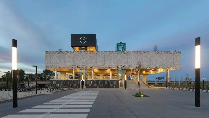 avondbeeld van het entreegebied met symmetrische verlichting en zicht op de decoratieve betonnen rand