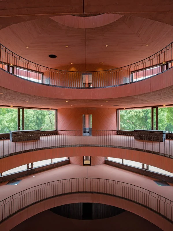 binnenzicht op het centrale atrium van pve ines met gelaagde betonnen galerijen en zachte daglichtinval foto pve architects