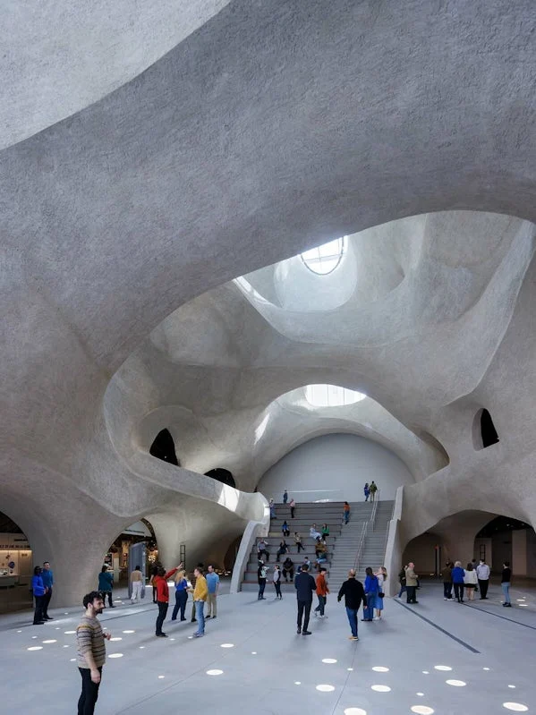 centrale ontmoetingsruimte met uitgesneden vormen en daglichtinval via sculpturale openingen