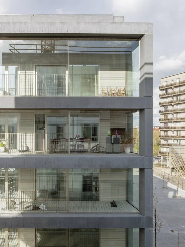 detail van woonlagen met zichtbare betonstructuur en grote glasvlakken