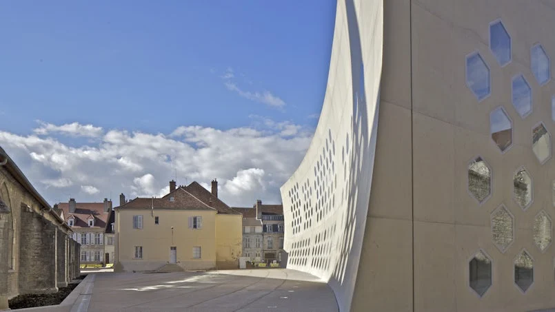 gebogen gevelwand in licht beton met variabele openingen een architectonisch statement in het straatbeel