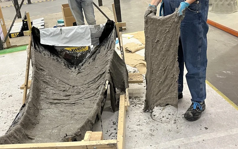 Het behangen van een textiele mal met in beton gedrenkte jute (foto: Tektoniek)