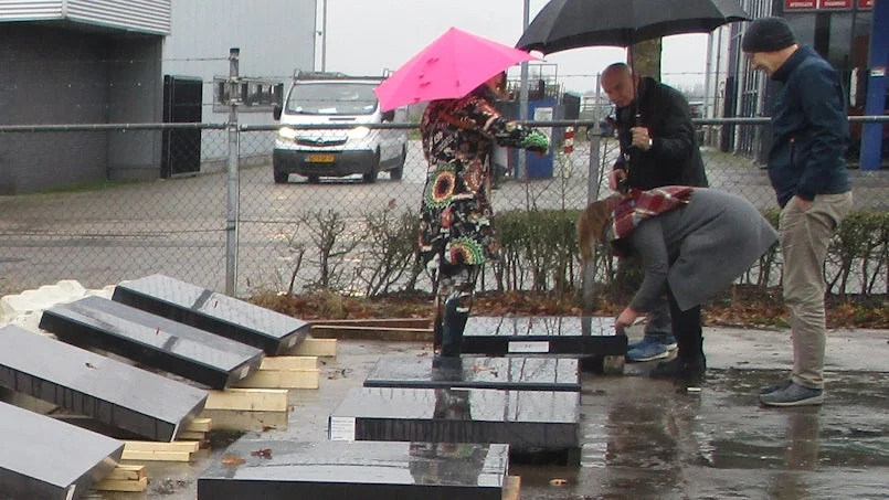 juryleden onder paraplu beoordelen zwartbetonpanelen op locatie – regenachtige testomstandigheden