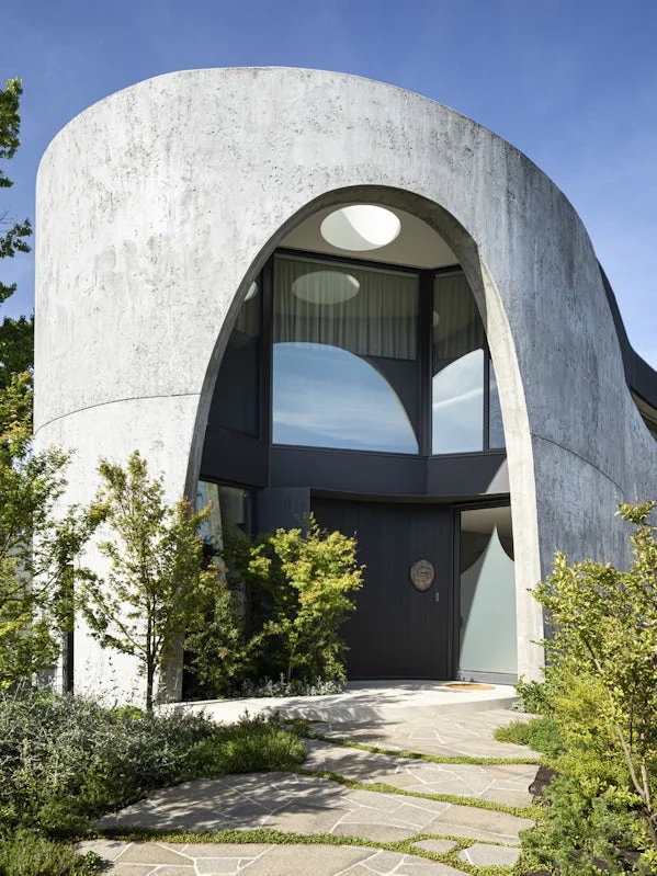karaktervolle entree met betonnen rondboog expressieve vormentaal als visitekaartje van de woning