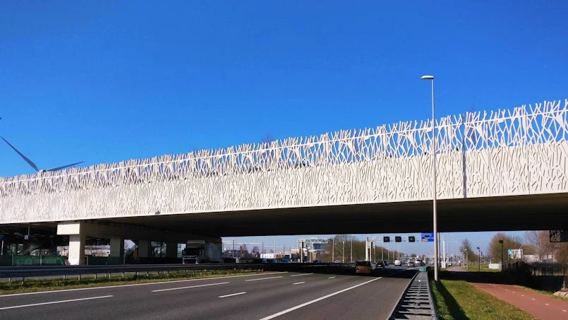 landschappelijke context met het gebouw als brugstructuur ondersteund door witte takvormige betonelementen