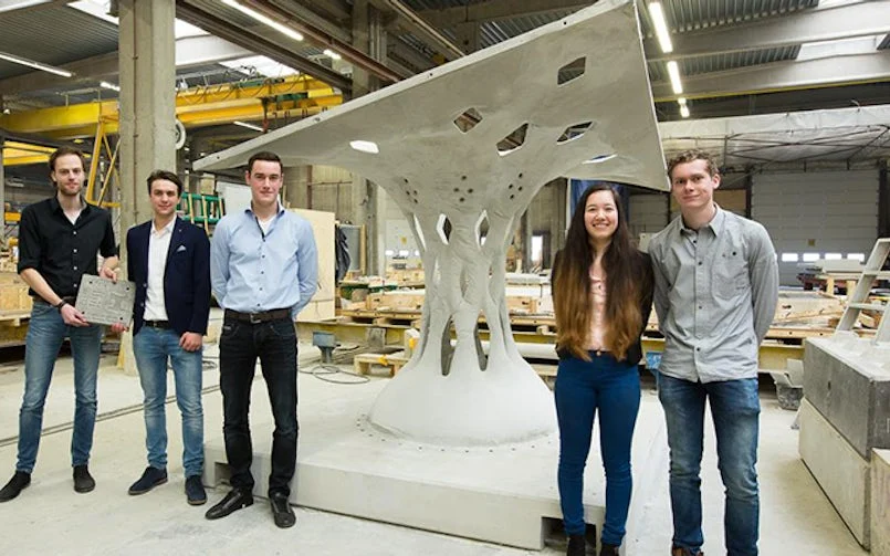 team poseert bij dubbelgekromd betonelement uit textielbekisting – innovatieve vormgeving via flexibele mallen