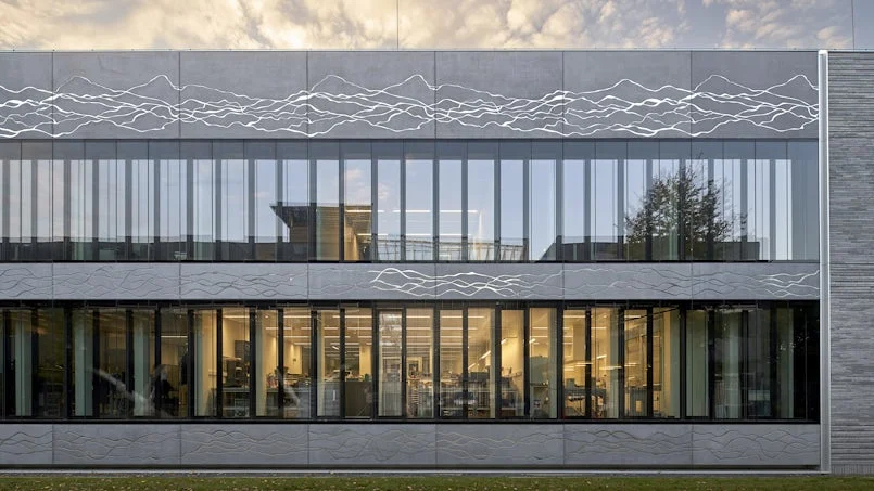 voorgevel van het esl gebouw met horizontale belijning en subtiel relief dat stromende patronen verbeeldt