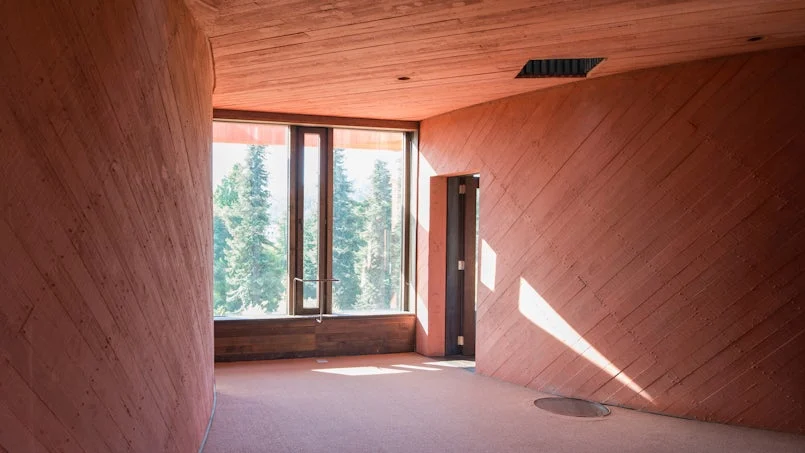 zicht vanuit een woonruimte in pve ines met betonnen wanden en houten kozijnen foto pve architects