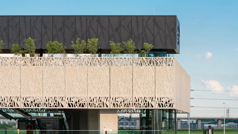 zijaanzicht van de betonnen takkenstructuur gecombineerd met een zwarte bovenbouw en vegetatie op het dak